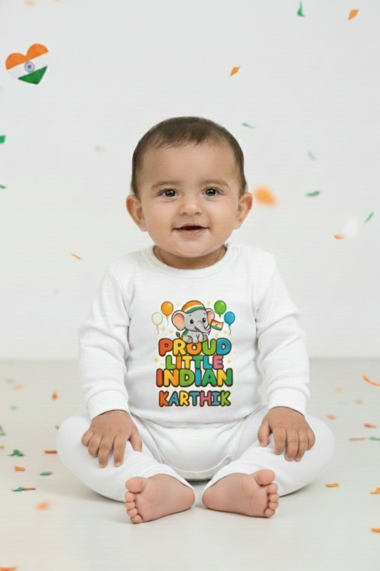 Baby wearing a white onesie with colorful text and graphics, sitting on a white floor with scattered colored confetti.