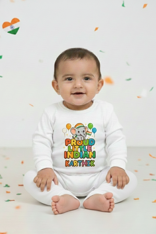 Baby wearing a white onesie with colorful text and graphics, sitting on a white floor with scattered colored confetti.